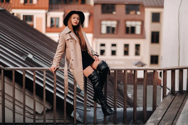 Stylish Young Woman Beige Coat Black Hat Sits Rooftop City — Stock Photo, Image