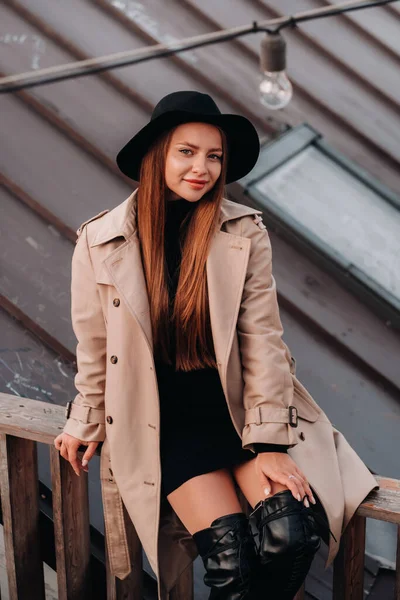 Stylish Young Woman Beige Coat Black Hat Sits Rooftop City — Stock Photo, Image