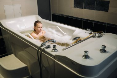 Küçük bir kız mineral banyosunda ameliyat oluyor. Hasta mineral inci banyosu ile su tedavisi görüyor..