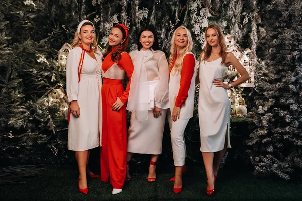 お祝いの白い服と赤い服のセクシーな女性がクリスマスの背景に立つ — ストック写真