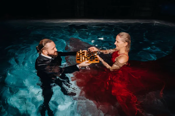 Hombre Traje Una Chica Vestido Rojo Juegan Ajedrez Agua Piscina — Foto de Stock