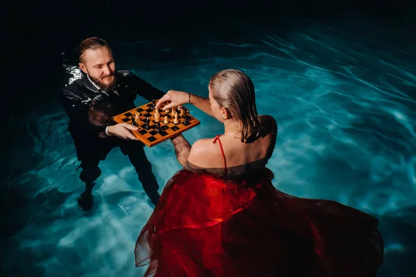 Hombre Traje Una Chica Vestido Rojo Juegan Ajedrez Agua Piscina — Foto de Stock