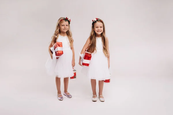 Dwie Małe Dziewczynki Białych Sukienkach Prezentami Świątecznymi Białym Tle Uśmiech — Zdjęcie stockowe