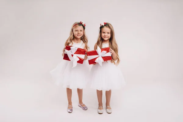 Två Små Flickor Vita Klänningar Med Julklappar Vit Bakgrund Leende — Stockfoto