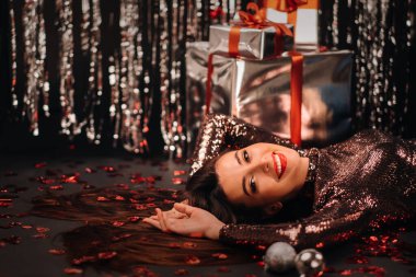 Kalpler ve hediyeler şeklinde konfeti içinde yerde parlak giysiler içinde yatan bir kızın en iyi görüntüsü..