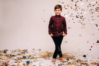 Güzel bir çocuk ayağa kalkar ve üzerine konfeti düşer..