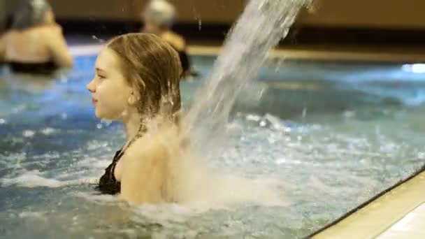 Menina sob uma cachoeira com o fluxo de água no parque aquático — Vídeo de Stock