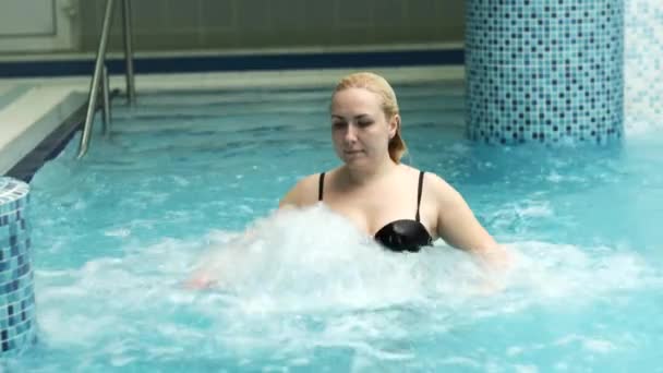 穿着泳衣的女孩站在一个水煮沸的池子里，被浇上了水 — 图库视频影像