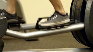 Bir atlet elipsoid simülatörle koşar. Spor salonunda bir elipsoidin üstünde antrenman