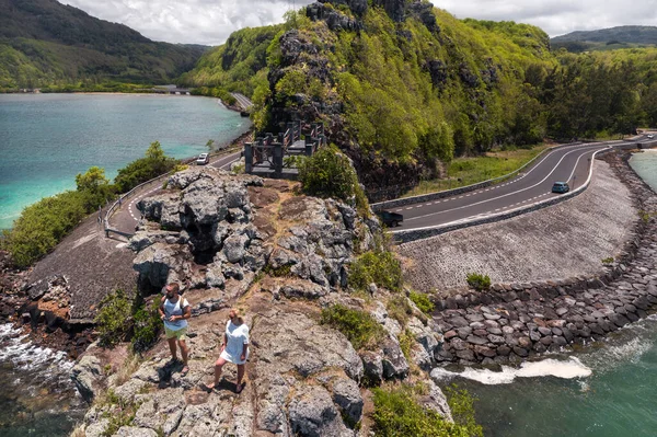 The couple stands on the edge of a cliff on the island of Mauritius.An unusual road to the islands of Mauritius