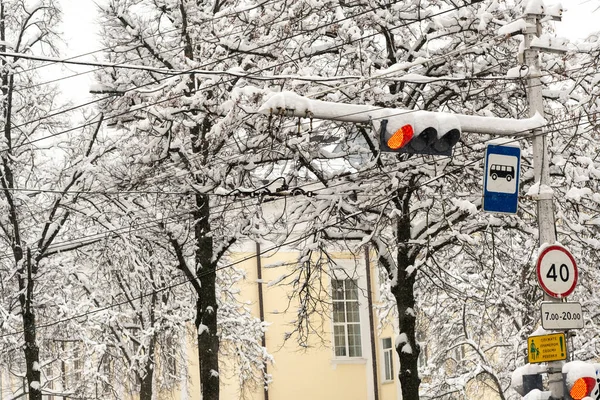 A working traffic light on a city street in winter.The red light of the traffic light is on.