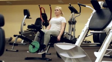 Kız spor salonundaki koşu bandında bacaklarını sallıyor.