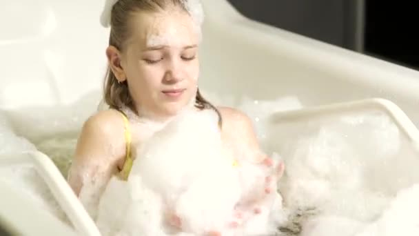 Una niña pequeña toma el procedimiento en un baño mineral. El paciente recibe tratamientos de agua con un baño de perlas minerales. — Vídeo de stock