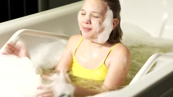 A little girl takes the procedure in a mineral bath. The patient receives water treatments with a mineral pearl bath. — Stock Video