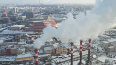 Kış şehrinde fabrika bacaları tütüyor. Hava kirliliği kavramı. Endüstriyel atıklarla çevre kirliliği