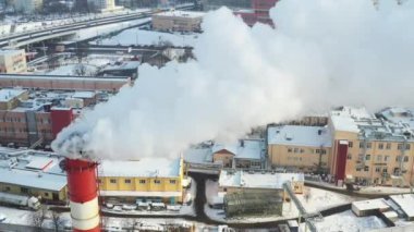 Kış şehrinde fabrika bacaları tütüyor. Hava kirliliği kavramı. Endüstriyel atıklarla çevre kirliliği