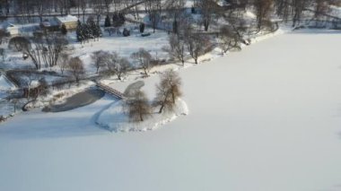 Loshitsky Parkı 'nda kışın köprüsü olan gölde bir ada. Minsk, Belarus.
