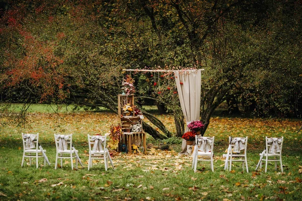 Autumn wedding ceremony on the street on the green lawn.Decor with arches of fresh flowers for the ceremony.