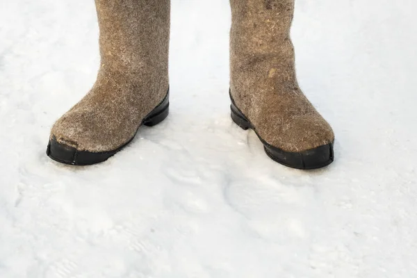close up of felt boots standing in the snow.