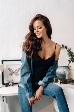 Uzun saçlı bir esmer masanın içinde poz veriyor..