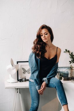 Uzun saçlı bir esmer masanın içinde poz veriyor..