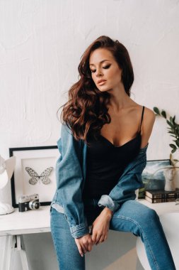 Uzun saçlı bir esmer masanın içinde poz veriyor..