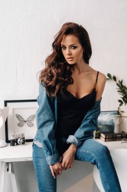 Uzun saçlı bir esmer masanın içinde poz veriyor..