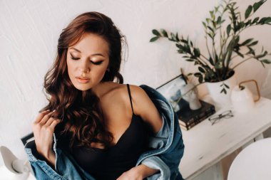 Uzun saçlı bir esmer masanın içinde poz veriyor..