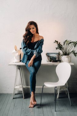 Uzun saçlı bir esmer masanın içinde poz veriyor..