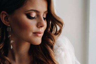 Şatafatlı bir gelinin yakın plan portresi. Sabahları kendi iç mekânında gelinlik giyiyor.