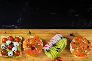 Tahtada balık, peynir, et ve sebzeli çeşitli sandviçler var..