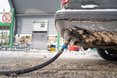 Kışın benzin istasyonunda tamponun dibindeki arabayı benzinle doldurmak..