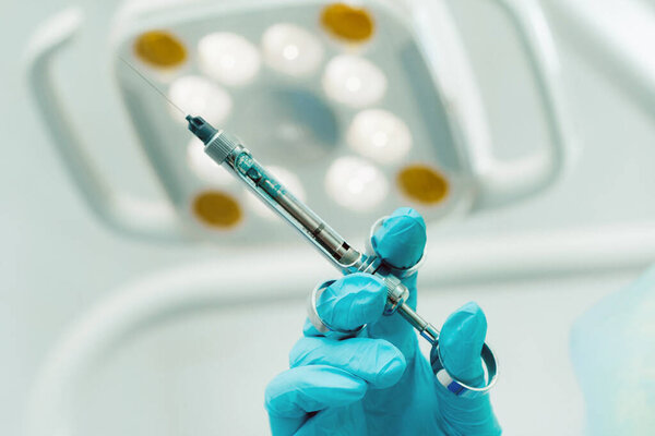 close-up of a dentist's hand holding an injection syringe for a patient in the office.