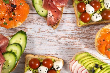 Tahta masada balık, peynir, et ve sebzeli sandviçler duruyordu..