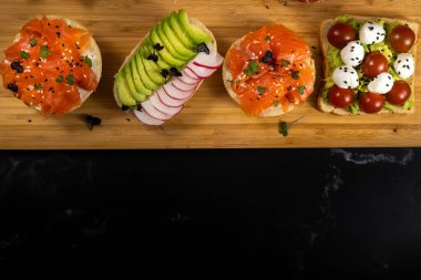 Tahtada balık, peynir, et ve sebzeli çeşitli sandviçler var..