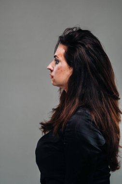 İzole edilmiş gri arka planda siyah elbiseli bir kadın. Kadınlara şiddet.