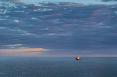 Açık Baltık Denizi 'nde sarı bir gemi. Bulutlarda gün batımı. Letonca,