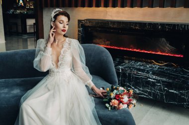 Şık, kızıl saçlı, kolları ve iç tarafında buketi olan bir gelin..