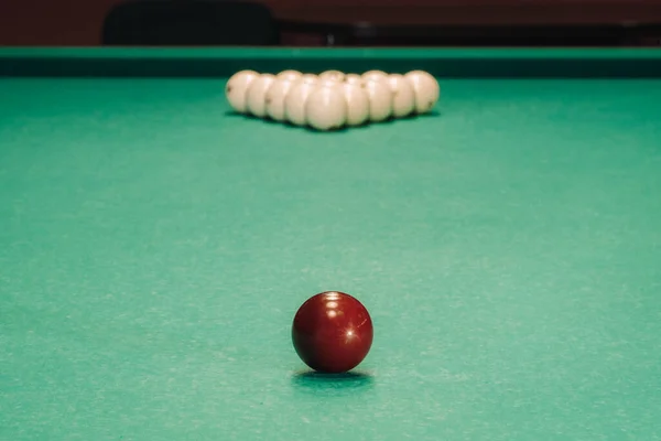 They play pool on a green table.The balls are placed in a triangle on the table