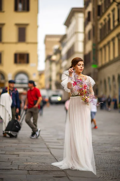 a bride in a wedding dress with a Venetian mask in her hands in Florence.Italy.