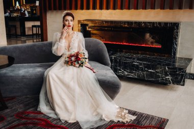 Şık, kızıl saçlı, kolları ve iç tarafında buketi olan bir gelin..