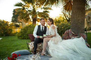 Yeni evlilerin akşam yemeği gün batımında çimenlikte. Fransa 'da bir çift oturur ve gün batımında çay içer..