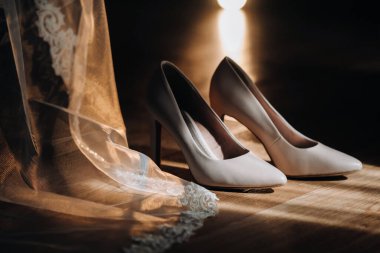 Beyaz düğün ayakkabıları sahanın üzerinde duruyor. Elbisenin yanında..