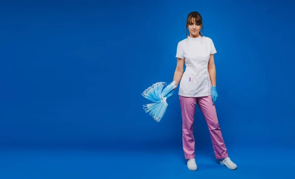 Uma Menina Médico Fundo Azul Detém Monte Máscaras Protetoras Suas — Fotografia de Stock