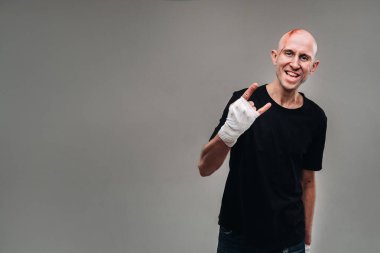 Eli siyah bir tişörte sarılı, gri bir arka planda uyuşturucu bağımlısı ve ayyaş gibi görünen hırpalanmış bir adam..