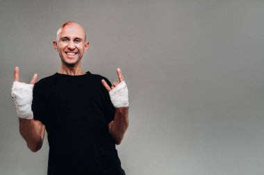 Eli siyah bir tişörte sarılı, gri bir arka planda uyuşturucu bağımlısı ve ayyaş gibi görünen hırpalanmış bir adam..