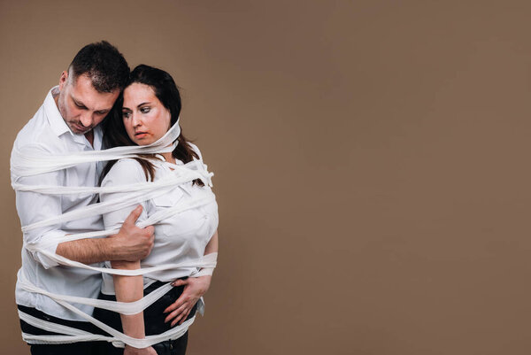 Агрессивный мужчина обнимает избитую женщину и завязывается в бинты. Бытовое насилие.