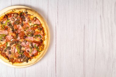 Hafif ahşap arka planda dana eti ve mantarlı lezzetli büyük pizza.