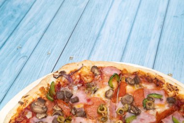 Mavi ahşap arka planda dana eti ve mantarlı lezzetli büyük pizza.