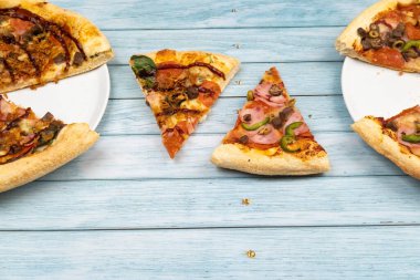 Mavi ahşap arka planda iki farklı lezzetli büyük pizza.